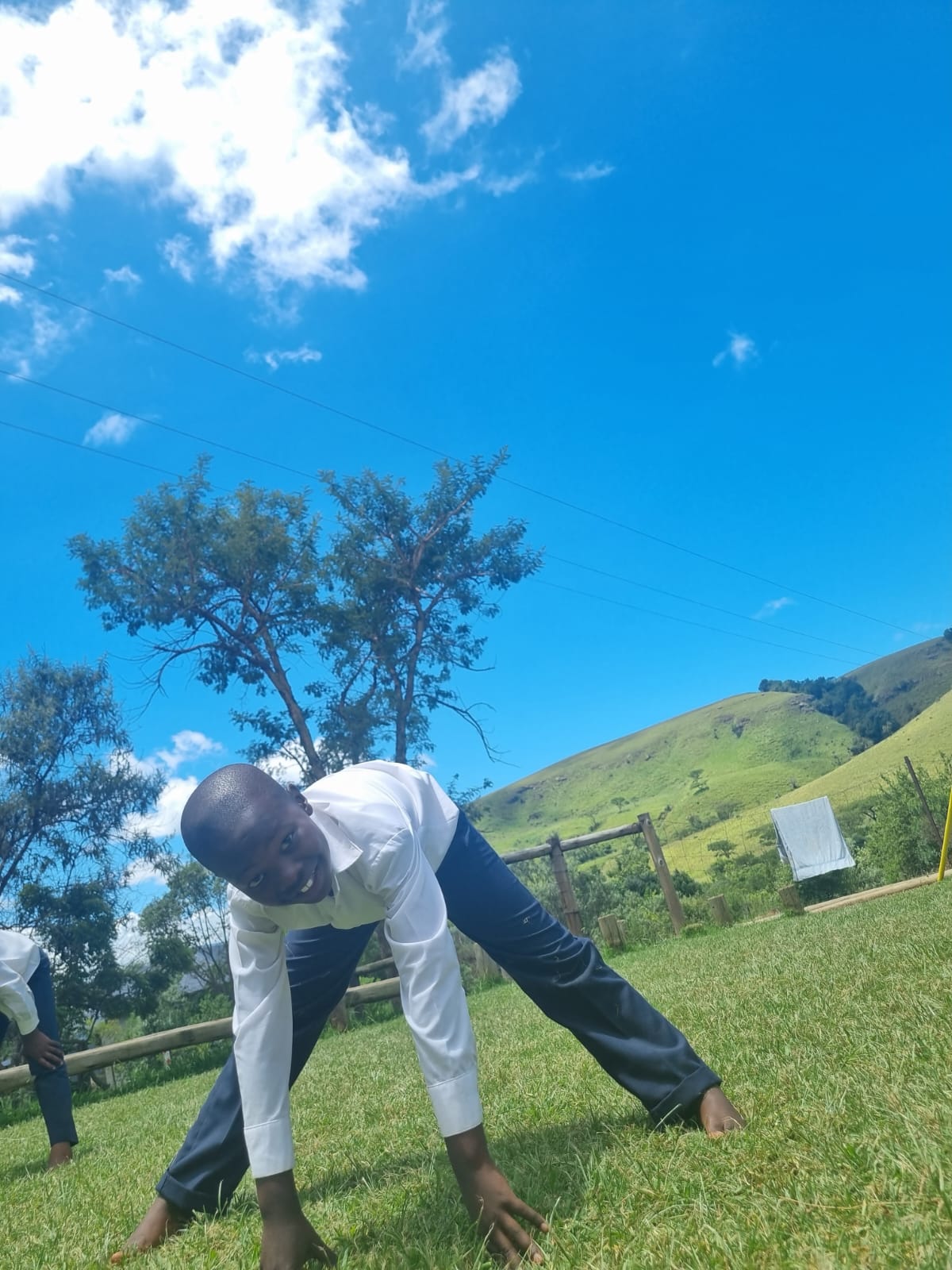 Boy in gecko pose against the blue Drakensberg sky
