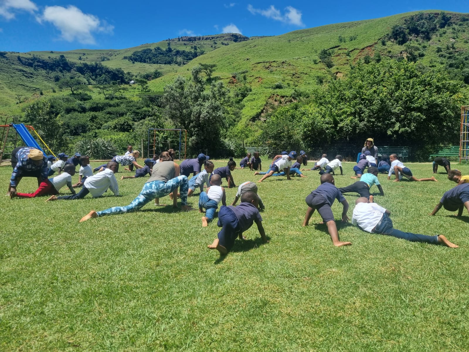 Children doing gecko movements on the grass